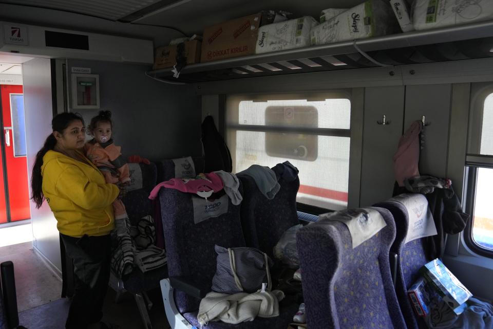 FILE - A woman with a child stays inside a train, using as a shelter, in Iskenderun city, southern Turkey, on Feb. 14, 2023. Hundreds of thousands of people are seeking shelter after the Feb. 6 earthquake in southern Turkey left homes unlivable. Many survivors have been unable to find tents or containers dispatched to the region by the government and aid agencies, Instead they have sought refuge in any structure that can protect them from the winter conditions, including greenhouses, rail carriages and factories. (AP Photo/Hussein Malla)