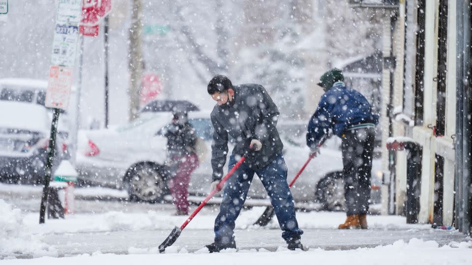 People clear a sidewalk during a winter snow storm in Philadelphia. - Matt Rourke/AP