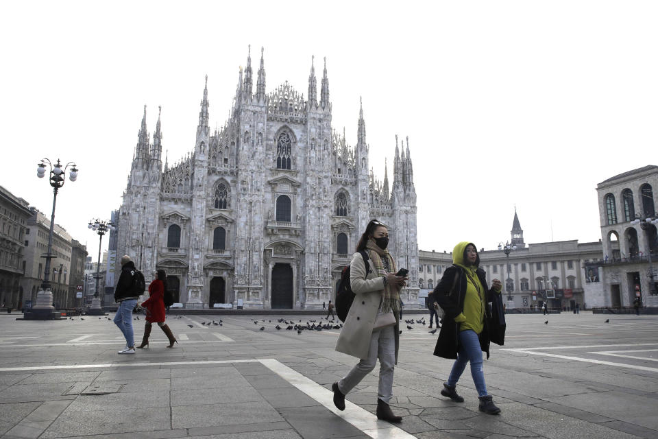 A woman wearing a sanitary mask walks past the Duomo gothic cathedral in Milan, Italy, Sunday, Feb. 23, 2020. A dozen Italian towns saw daily life disrupted after the deaths of two people infected with the virus from China and a pair of case clusters without direct links to the outbreak abroad. A rapid spike in infections prompted authorities in the northern Lombardy and Veneto regions to close schools, businesses and restaurants and to cancel sporting events and Masses. (AP Photo/Luca Bruno)