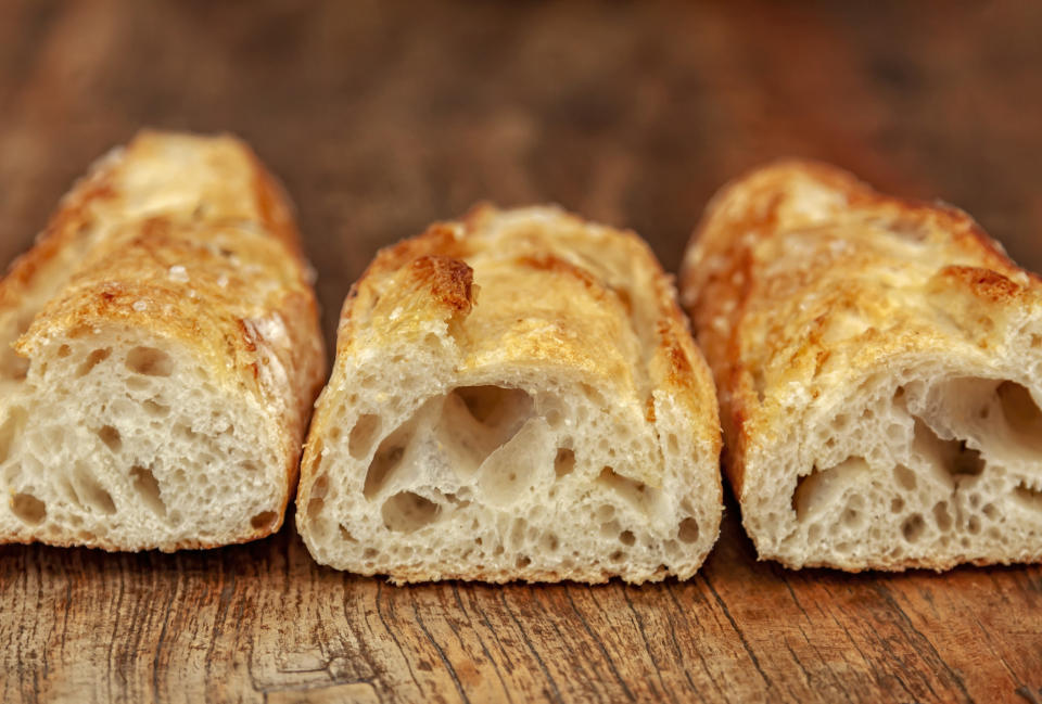 Three sliced baguettes on rustic wooden table.