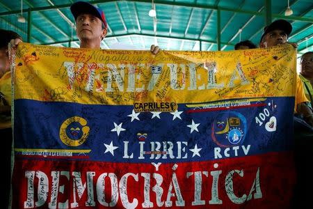 Opposition supporters hold a Venezuelan flag that reads "Venezuela free and democratic" during a peaceful rally to demand a referendum to remove President Nicolas Maduro in Caracas, Venezuela June 12, 2016. REUTERS/Ivan Alvarado