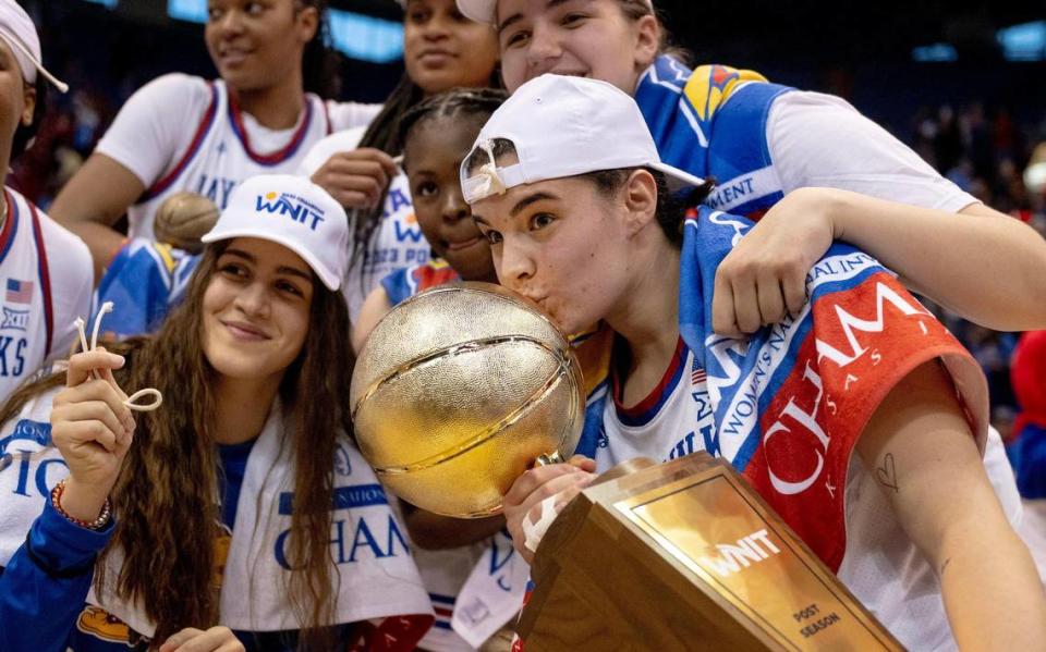 Kansas guard Mia Vuksic (4) kisses the WNIT championship trophy after Kansas defeated Columbia 66-59 in the final of the WNIT, Saturday, April 1, 2023, in Lawrence, Kan.