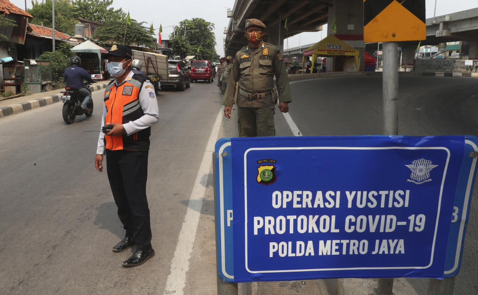 Officers stand guard at a police check point as the large-scale restriction is imposed to curb the spread of the coronavirus outbreak in Jakarta, Indonesia, Monday, Sept. 14, 2020. Indonesia's capital on Monday begins to reimpose large-scale social restrictions to control a rapid expansion in the virus cases. (AP Photo/Achmad Ibrahim)