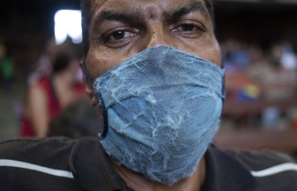 Un hombre, con mascarilla para protegerse de la propagación del coronavirus, espera para recibir comida en una iglesia en el vecindario de El Cementerio, en Caracas, Venezuela, el 22 de mayo de 2020. (AP Foto/Ariana Cubillos)