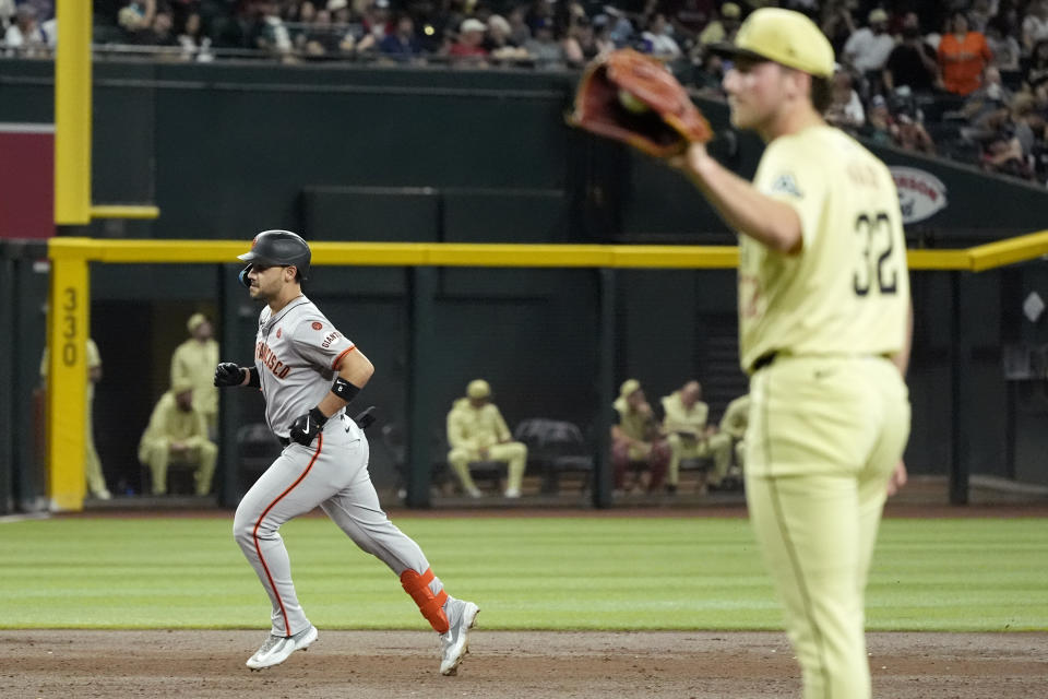 San Francisco Giants' Michael Conforto, left, rounds the bases after hitting a three-run home run against Arizona Diamondbacks starting pitcher Brandon Pfaadt, right, during the third inning of a baseball game Tuesday, Sept. 24, 2024, in Phoenix. (AP Photo/Ross D. Franklin)