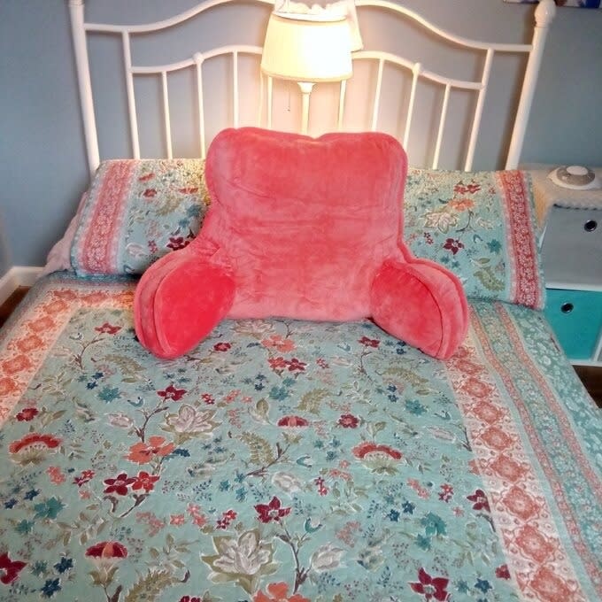 reviewer image of the pink backrest pillow on a bed