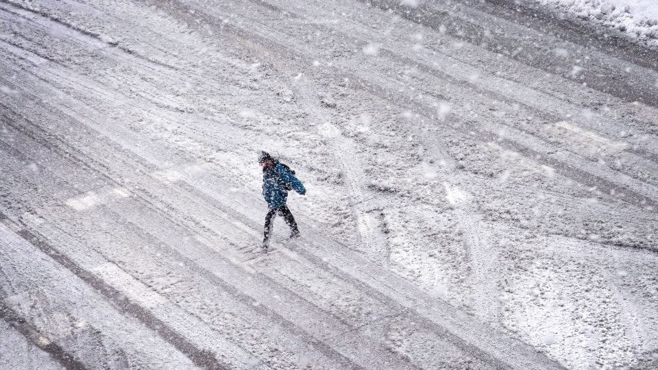 A pedestrian navigates a snow-covered street in Iowa City, Iowa, on Tuesday. - Scott Olson/Getty Images