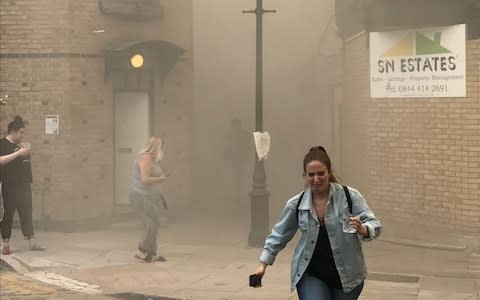 Pedestrians flee smoke - Credit: @SamuelsBobby/via Reuters