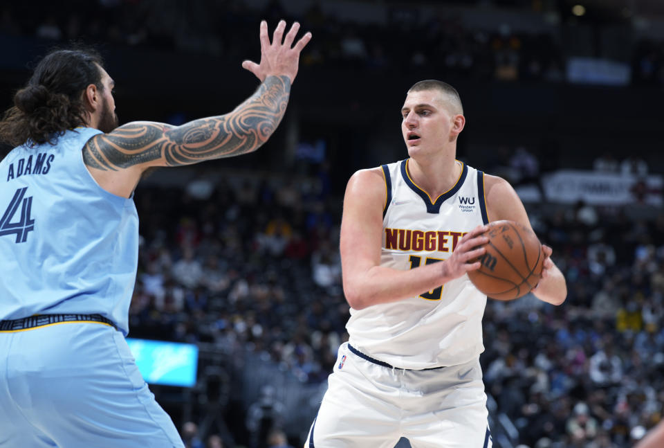 Denver Nuggets center Nikola Jokic, right, looks to pass the ball as Memphis Grizzlies center Steven Adams defends during the first half of an NBA basketball game Friday, Jan. 21, 2022, in Denver. (AP Photo/David Zalubowski)