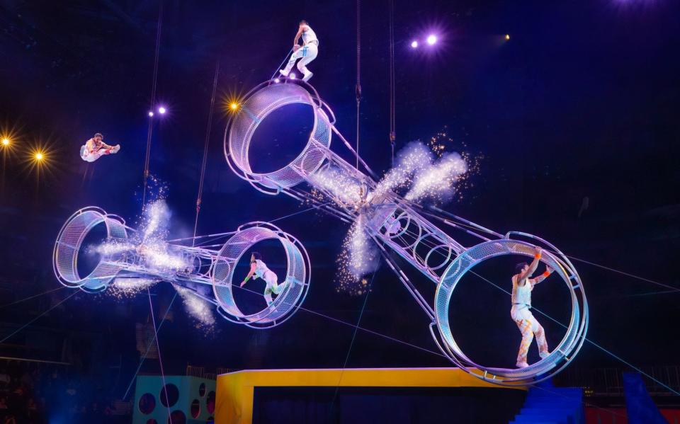 Acrobatic daredevils perform coordinated leaps and somersaults on spinning apparatuses suspended above the stage in the Ringling Bros. and Barnum & Bailey Circus.