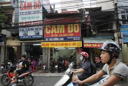 People ride motorcycles past pawn shops in Hanoi September 9, 2013. REUTERS/Kham