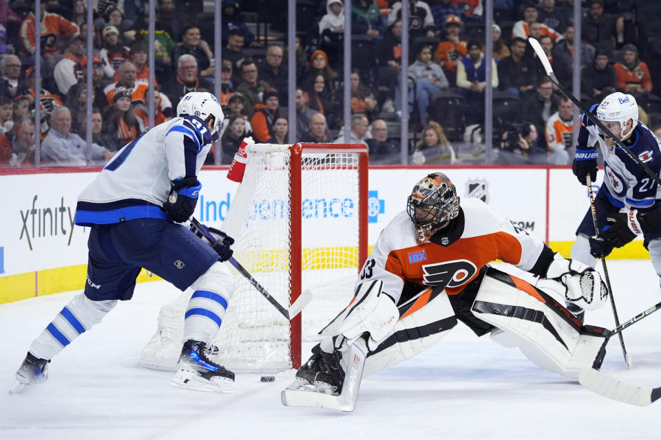 Winnipeg Jets' Kyle Connor, left, scores behind Philadelphia Flyers' Samuel Ersson during the third period of an NHL hockey game, Thursday, Feb. 8, 2024, in Philadelphia. (AP Photo/Matt Slocum)