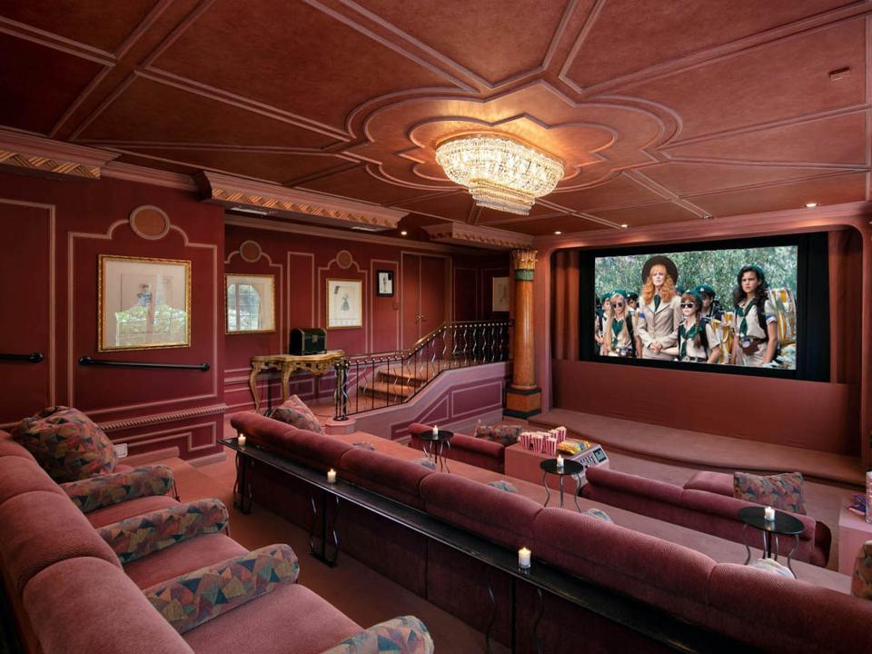 a movie theater with dark pink seats by a screen