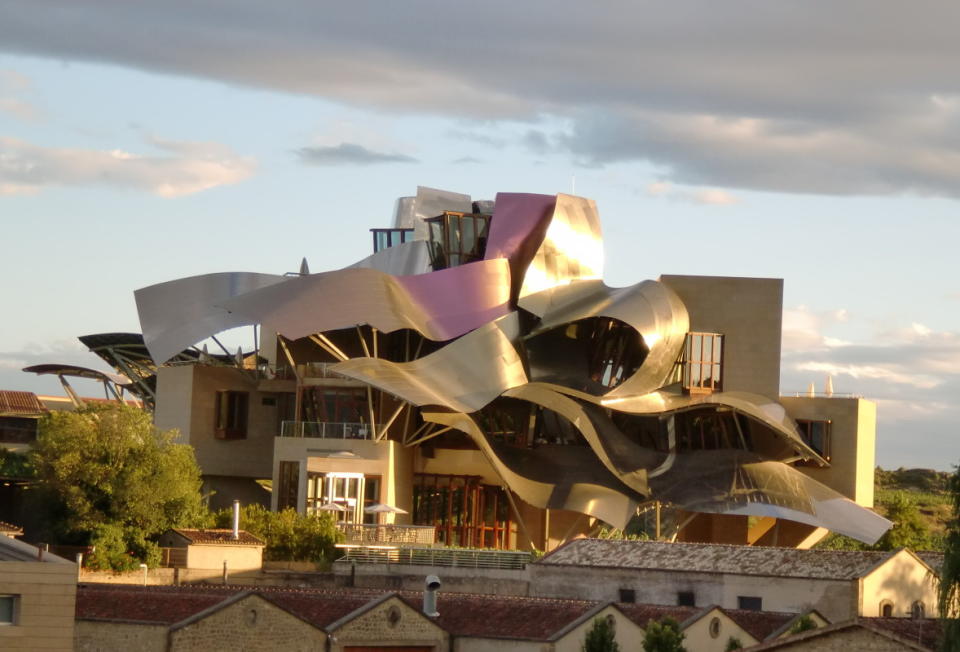 <p>Courtesy of Marqués de Riscal</p><p>At the heart of the <strong>Marqués de Riscal City of Wine </strong>stands the jewel in the crown of the Marriot International hotel chain: the Hotel Marqués de Riscal, A Luxury Collection Hotel. Designed by Frank O. Gehry, one of the world’s top architects, responsible, among other major works, for the Bilbao Guggenheim Museum, the hotel combines the most deeply rooted winemaking tradition with an avant-garde design, luxury and the most advanced technology of the 21st century.</p><p>Inaugurated on 10 October 2006, it stands out for its <strong>spectacular forms and skyline</strong>. This unique building contrasts elegantly with the headquarters of the wineries, a building dating from 1858 and designed by the architect Ricardo Bellsola, situated between the vineyards and the medieval town of Elciego, in the centre of the Rioja Alavesa.</p><p>It offers all the luxury standards and services that you would expect from a hotel with <strong>The Luxury Collection brand</strong>, the Marriot International chain, and with the personal stamp of Frank Gehry: the titanium and steel of the roofing panels and the asymmetry of the wall and floor tiles. The 61 luxury bedrooms, 10 of them suites, split between two buildings linked by a <strong>spectacular raised walkway</strong>, are all different and unique, both in their forms and for their outlook.</p><p><a href="https://www.marquesderiscal.com/en/marques-de-riscal-hotel" rel="nofollow noopener" target="_blank" data-ylk="slk:Click here to make a reservation;elm:context_link;itc:0;sec:content-canvas" class="link ">Click here to make a reservation</a></p>