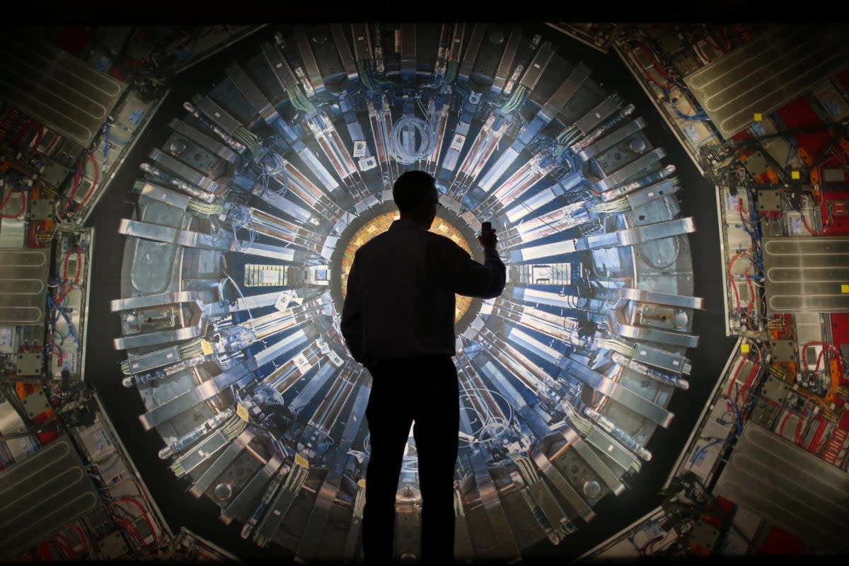 A visitor takes a photo of an image of the Large Hadron Collider at the Science Museum’s ‘Collider’ exhibition in 2013 (Getty) (Getty Images)