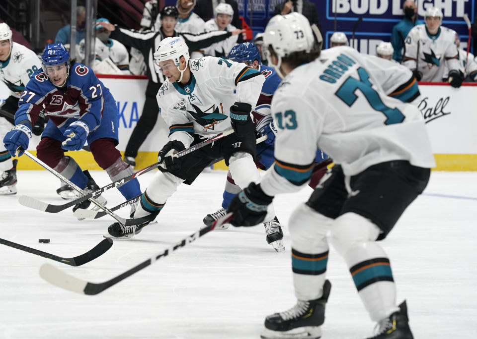 San Jose Sharks center Dylan Gambrell, center, passes the puck to center Noah Gregor, front, as Colorado Avalanche's Ryan Graves defends during the second period of an NHL hockey game Tuesday, Jan. 26, 2021, in Denver. (AP Photo/David Zalubowski)