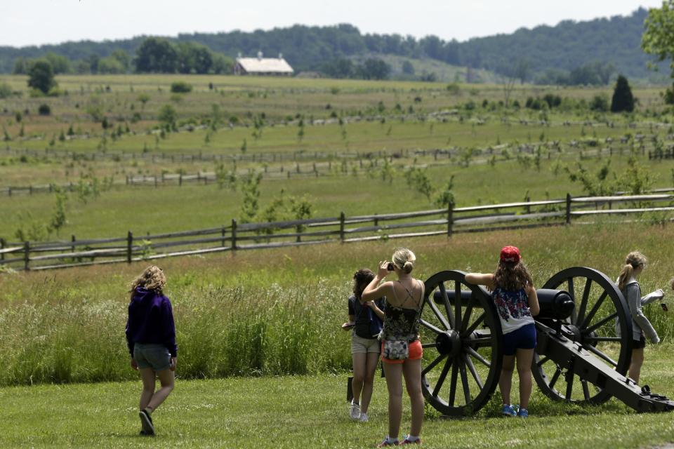 In this June 5, 2013 file photo tourist gather near a Confederate artillery piece that sit atop a ridge above the field of Pickett's Charge, in Gettysburg, Pa. As the 150th anniversary of the Battle of Gettysburg draws near the character and historic legacy of the town remain divided as hundreds of thousands of tourists visit the battlefield where so many died and development continues unabated around the site, drawing outlet shopping, restaurants and a casino. (AP Photo/Matt Rourke, File)