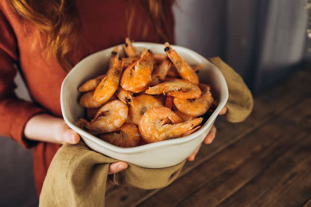 <p>Evgeniia Rusinova / Getty Images</p> A person holding a bowl of freshly cooked shrimp