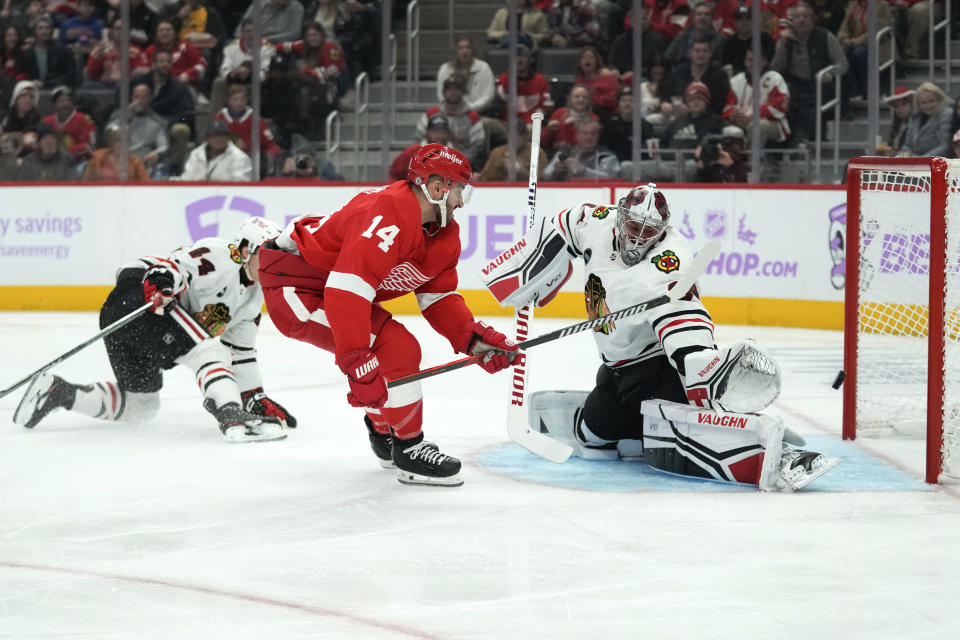 Detroit Red Wings center Robby Fabbri (14) shoots on Chicago Blackhawks goaltender Petr Mrazek (34) as Chicago Blackhawks' Wyatt Kaiser (44) defends in the second period of an NHL hockey game Thursday, Nov. 30, 2023, in Detroit. (AP Photo/Paul Sancya)