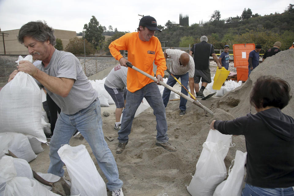 Volunteers, from left, Steve Hamilton, Thomas Lubboch and Becky Chen help fill sandbags before an expected storm Wednesday Feb. 26, 2014 in Glendora, Calif. Much-needed rain fell in Northern California on Wednesday at the outset of what the parched state hopes is the start to a one-two punch of stormy weather with a half inch of rain predicted. (AP Photo/Nick Ut )