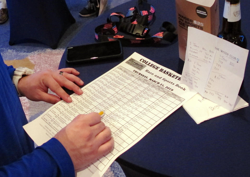 A gambler looks over a race and sports book sheet for the NCAA basketball tournament Thursday, March 21, 2019, at the Borgata casino in Atlantic City N.J. This is the first March Madness tournament since legal gambling expanded last year following a U.S. Supreme Court ruling involving a case brought by New Jersey. (AP Photo/Wayne Parry)