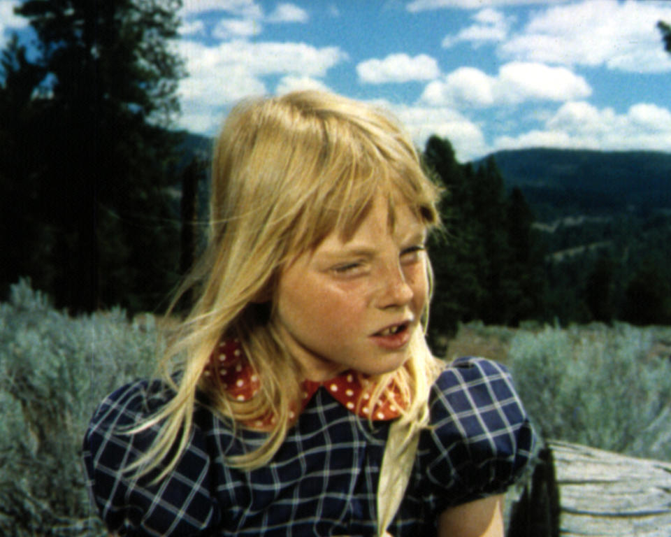 YoungJodie in braids and a checkered dress with a polka-dot scarf outdoors in a scene from "Napoleon and Samantha"