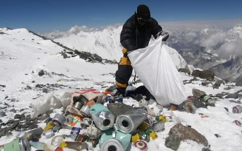  A Nepalese sherpa collects rubbish, left by climbers, during an Everest clean-up expedition - Credit: AFP