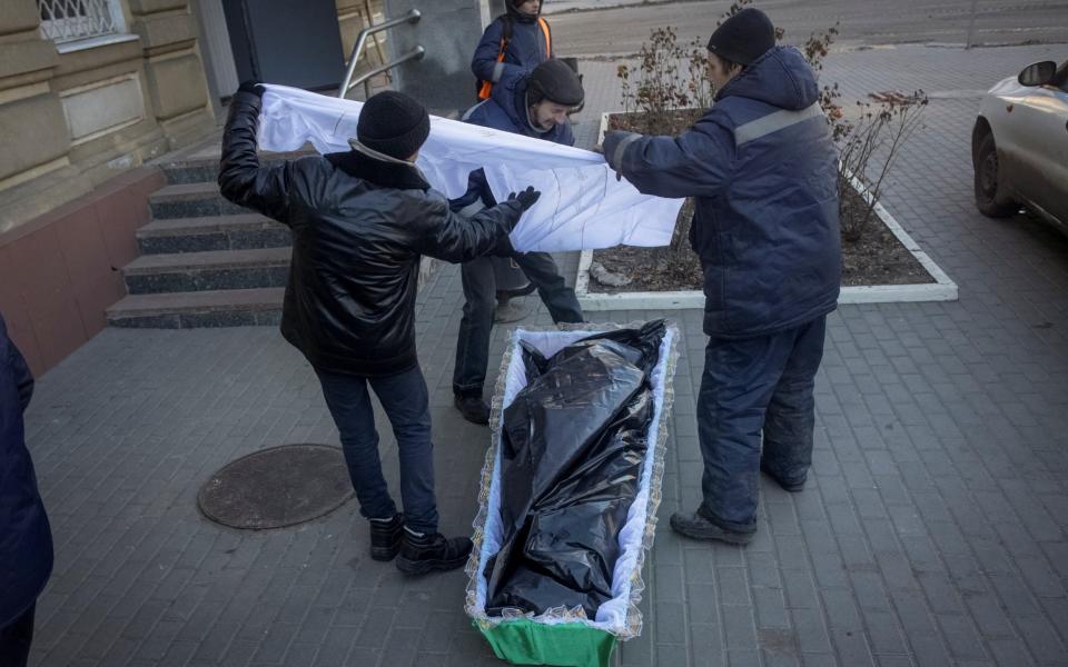 Funeral directors place a body of an unidentified local resident in a coffin in Bakhmut - REUTERS