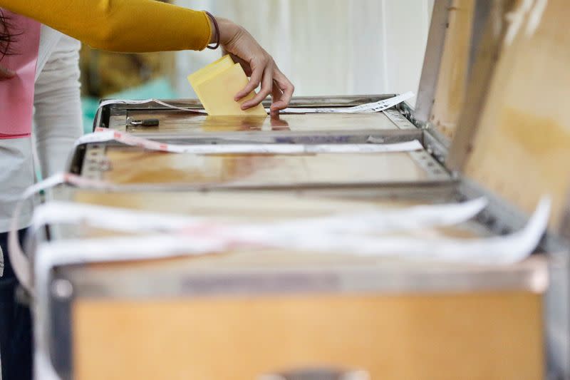 A Taiwanese casts their vote into a ballot box during the general elections in Kaohsiung