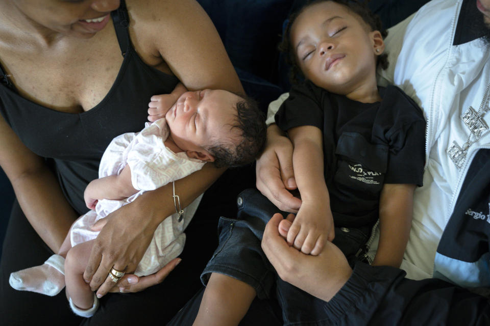 Aaliyah Wright, 25, of Washington, holds their newborn daughter Kali, as her husband Kainan Wright, 24, of Washington, holds their sleeping son Khaza, 1, during a visit to the children's grandmother in Accokeek, Md., Tuesday, Aug. 9, 2022. A landmark social program is being pioneered in the nation’s capital. Coined “Baby Bonds,” the program is designed to narrow the wealth gap. The program would provide children of the city’s poorest families up to $25,000 when they reach adulthood. (AP Photo/Jacquelyn Martin)