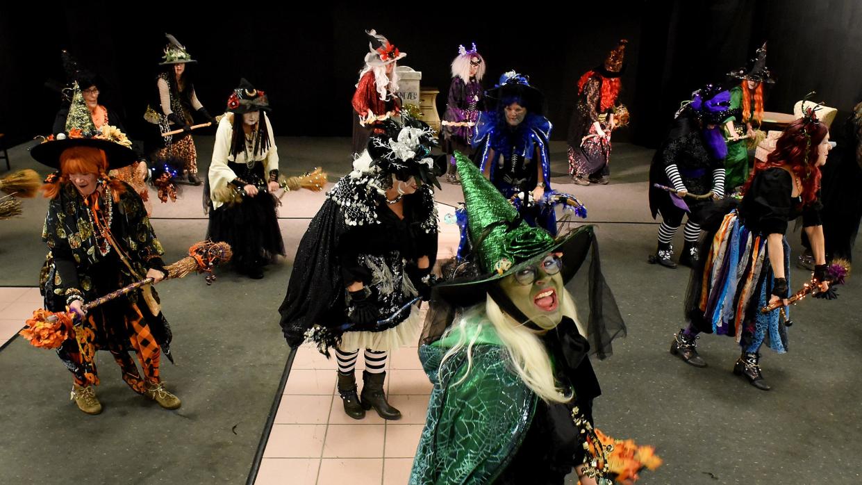 Valinda Jonas of Monroe (foreground), founder of the Lake Eerie Hexenbrut witches, cackles as she leads the warmup broom dance with members April 30 inside the Players Club at the Mall of Monroe.