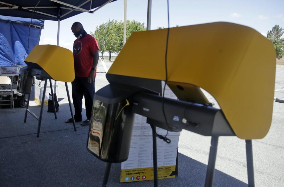 A man stands at an outdoor voting booth.