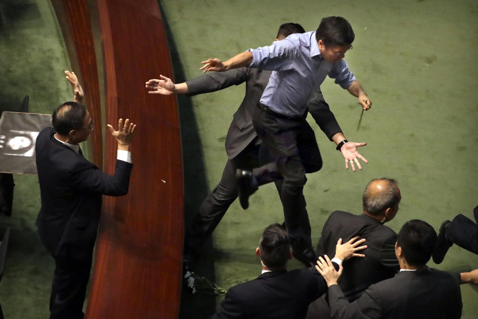 Pro-democracy lawmaker Au Nok-hin jumps off a desk to chase Hong Kong Chief Executive Carrie Lam as she leaves a question and answer session with lawmakers at the Legislative Council in Hong Kong, Thursday, Oct. 17, 2019. (AP Photo/Mark Schiefelbein)