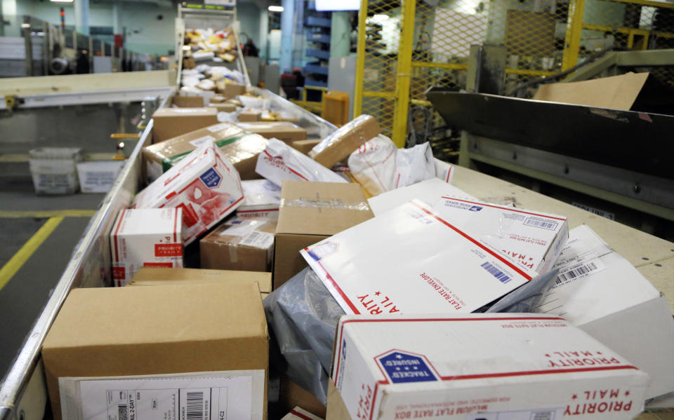 FILE- In this Dec. 14, 2017, file photo, packages travel on a conveyor belt for sorting at the main post office in Omaha, Neb. The city of New York and the state of California sued the U.S. Postal Service Tuesday, Oct. 22, 2019, to stop tens of thousands of cigarette packages from being mailed from foreign countries to U.S. residents, saying the smugglers are engaging in “cigarette tax evasion” while postal workers look the other way. (AP Photo/Nati Harnik, File)