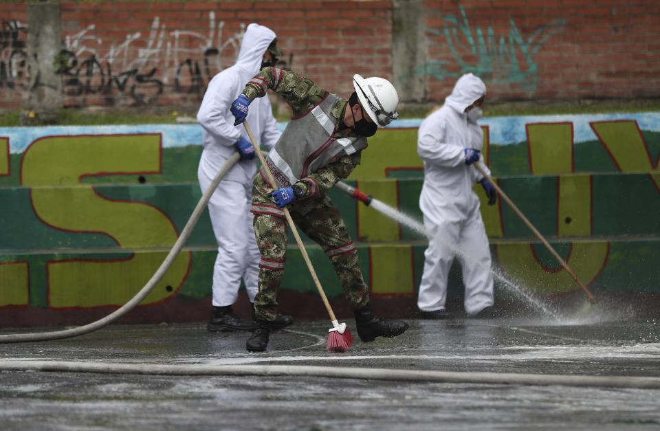 Soldados desinfectan una cancha de basketball en un parque en medio de la pandemia del nuevo coronavirus en el área San Cristóbal en Bogotá, Colombia, el martes 16 de junio de 2020. (AP Foto/Fernando Vergara)