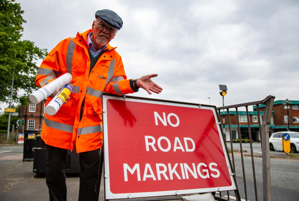 Peter Sharratt Stands next to a sign erected by the council that reads 'no road markings'. (SWNS)