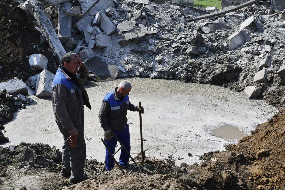 Workers stand next to a crater after night shelling in Kramatorsk, Ukraine, Thursday, May 5, 2022. (AP Photo/Andriy Andriyenko)