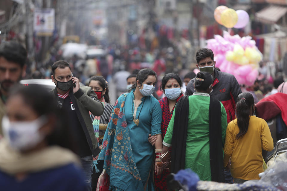 Indians, most of them, wearing face masks as a precautionary measure against the coronavirus crowd a Sunday market in Jammu, India, Sunday, Nov.22, 2020. (AP Photo/Channi Anand)