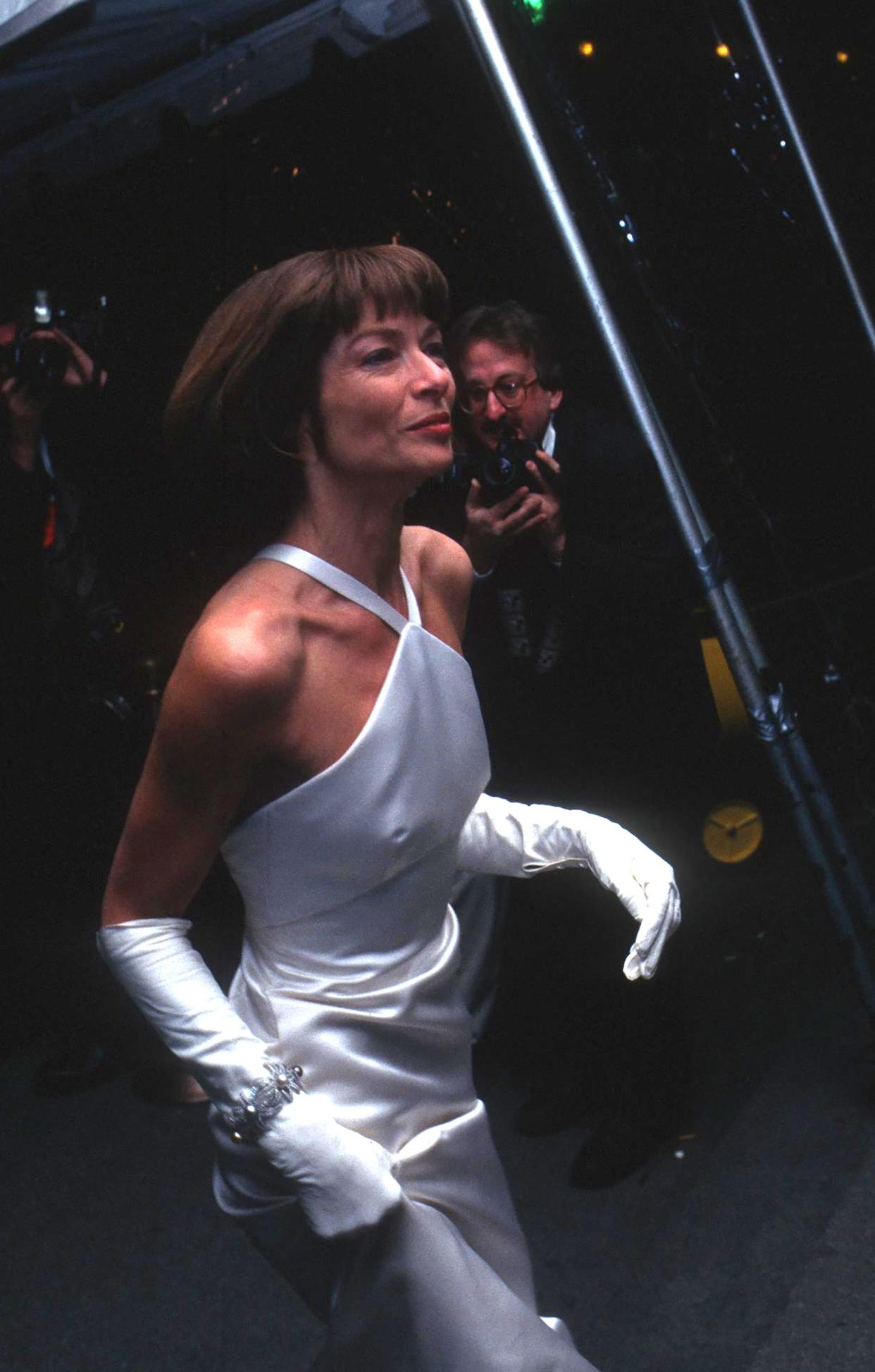 Anna Wintour arrives at the 1995 Met Gala in a white gown with elbow length gloves.