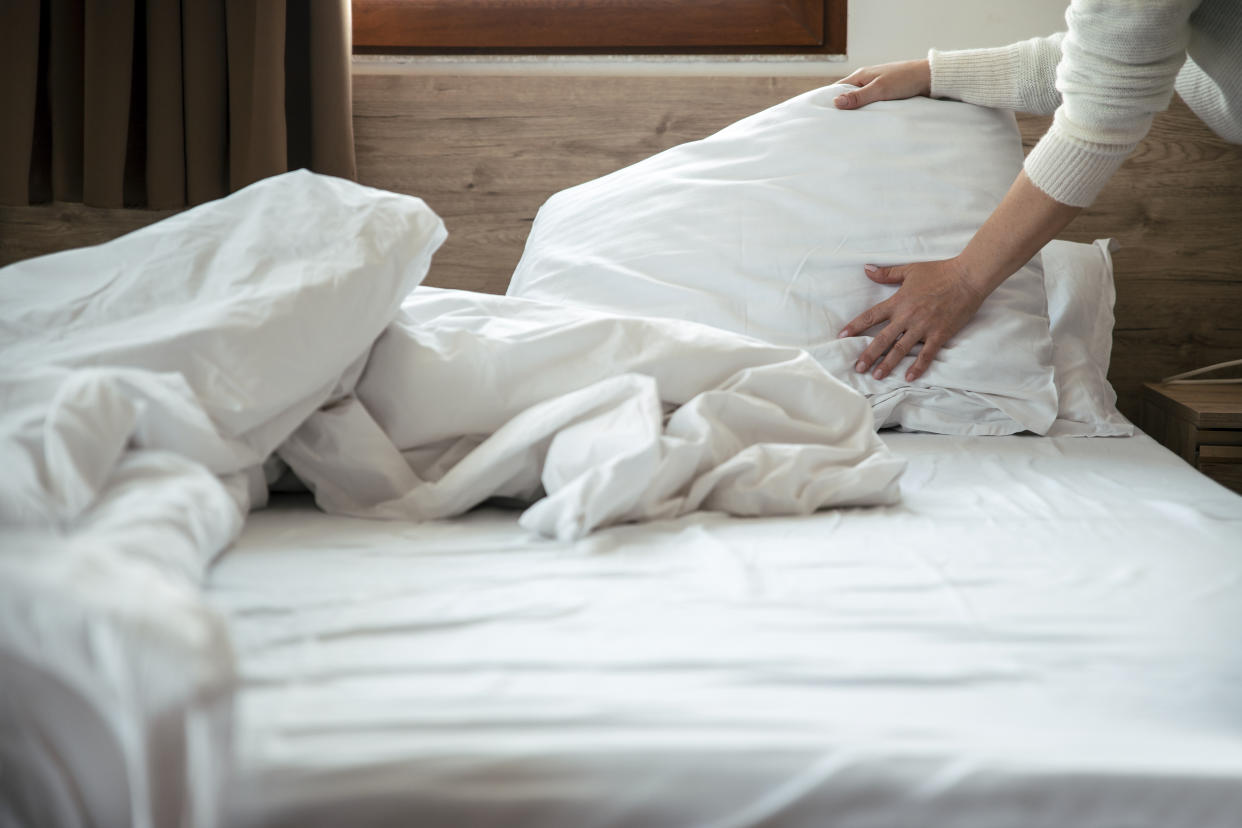 Daily housekeeping service. Maid Cleaning messy hotel bed cushion and duvet, changing bed sheets with clean. Selective focus. Copy space