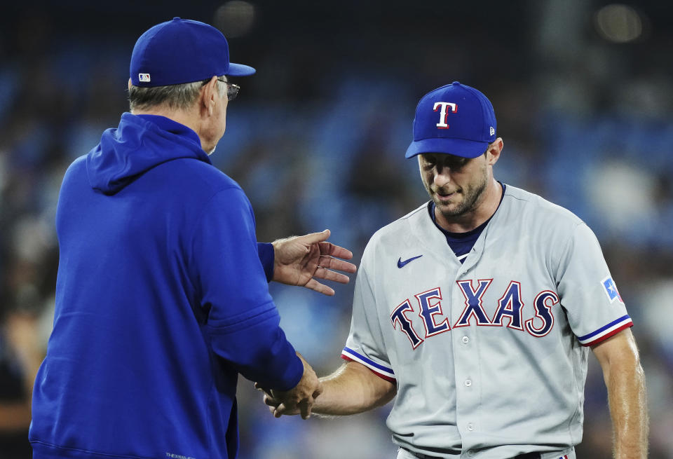 Texas Rangers starting pitcher Max Scherzer, right, is taken out of the baseball game against the Toronto Rangers by manager Bruce Bochy during the sixth inning Tuesday, Sept. 12, 2023, in Toronto. (Nathan Denette/The Canadian Press via AP)