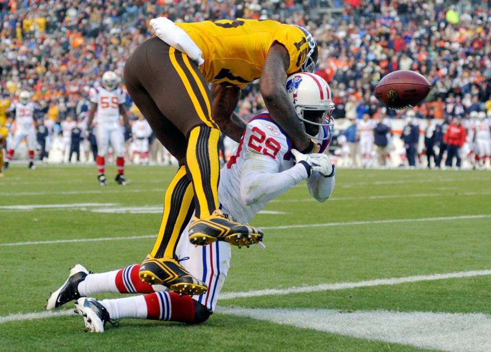 Denver Broncos wide receiver Brandon Marshall (15) breaks up a possible interception by New England Patriots' Shawn Springs (29) in overtime in an NFL football game Sunday, Oct. 11, 2009, in Denver.