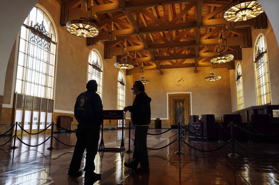 Visitors appear inside Union Station in Los Angeles on March 23, 2021. The Oscars are headed to the historic site for the first time this year. With wide open spaces and 65-foot high ceilings, it’s ideal for a big crew and cameras. It’s been used in car commercials, reality shows and procedurals. But its beamed ceilings, Spanish tile floors and regal bronze chandeliers really shine in cinema where it’s played train stations, banks, police stations, clubs and airports. (AP Photo/Chris Pizzello)