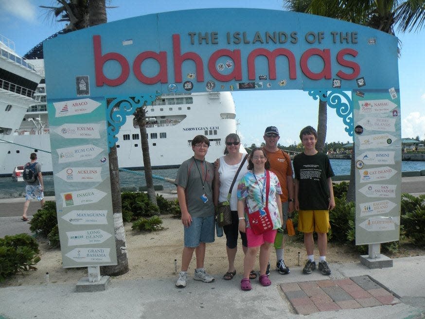 Renae Gregoire and her kids posing for a picture in front of a Bahamas sign on their first cruise.