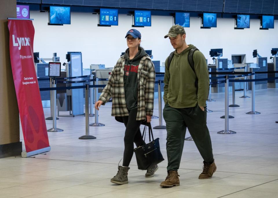 Passengers walk by an empty Lynx Air check-in counter at the international airport in Calgary on Feb. 23, 2024. Officials with the Calgary-based company announced Thursday evening that it is ceasing operations, after filing for creditor protection. 
