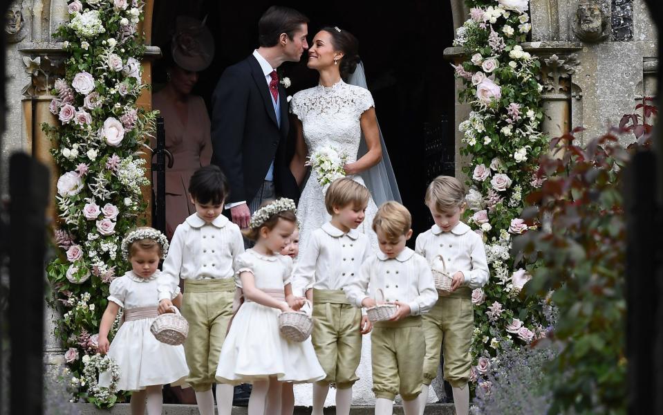 Pippa Middleton kisses her new husband James Matthews, following their wedding ceremony as the bridesmaids and pageboys walk ahead - Credit: Getty Images