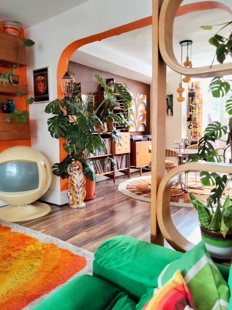 Colorful decorated living room with orange accents and green fabric couch.
