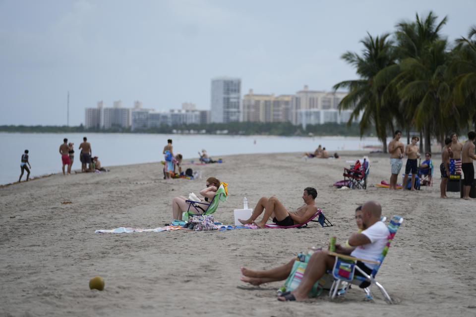 Beachgoers lounge in Crandon Park, Friday, July 28, 2023, in Key Biscayne, Fla. In the sweltering summer heat, nobody tries to cool off by jumping into a hot tub. In parts of Florida, however, that’s what the ocean has felt like. (AP Photo/Rebecca Blackwell)