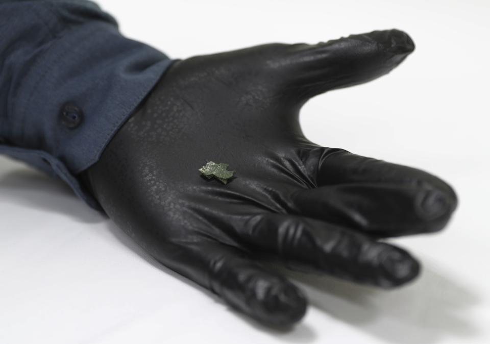 A member of the U.S. investigative team shows a piece of aluminium and composite debris that the U.S. Navy says came from a limpet mine attack on a Japanese-owned oil tanker are shown to journalists at a 5th Fleet base, during a trip organized by the Navy for journalists, near Fujairah, United Arab Emirates, Wednesday, June 19, 2019. Cmdr. Sean Kido of the U.S. Navy's 5th Fleet said Wednesday that the limpet mine used on a Japanese-owned oil tanker last week "bears a striking resemblance" to similar Iranian mines. (AP Photo/Kamran Jebreili)