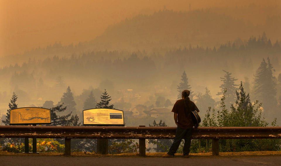 <p>Jason Wheeler looks out across the Columbia River from the north side of Bridge of the Gods at the smoky community of Cascade Locks, Ore. Sept. 5, 2017 after being evacuated from his home yesterday. (Photo: Chris Pietsch/The Register-Guard via AP) </p>